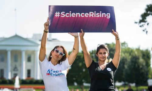 Two women holding a sign that says "Science Rising"