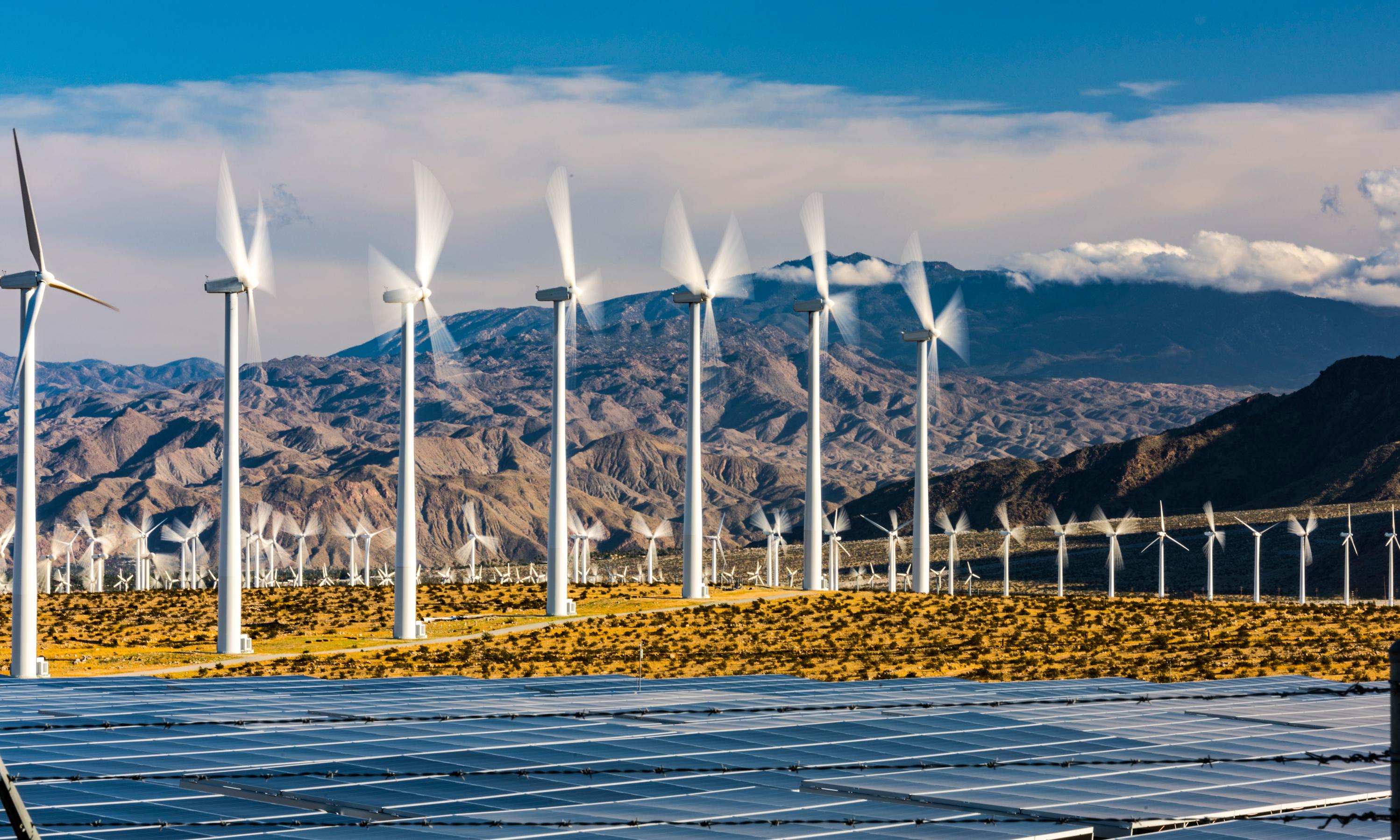 Wind turbines behind a solar farm
